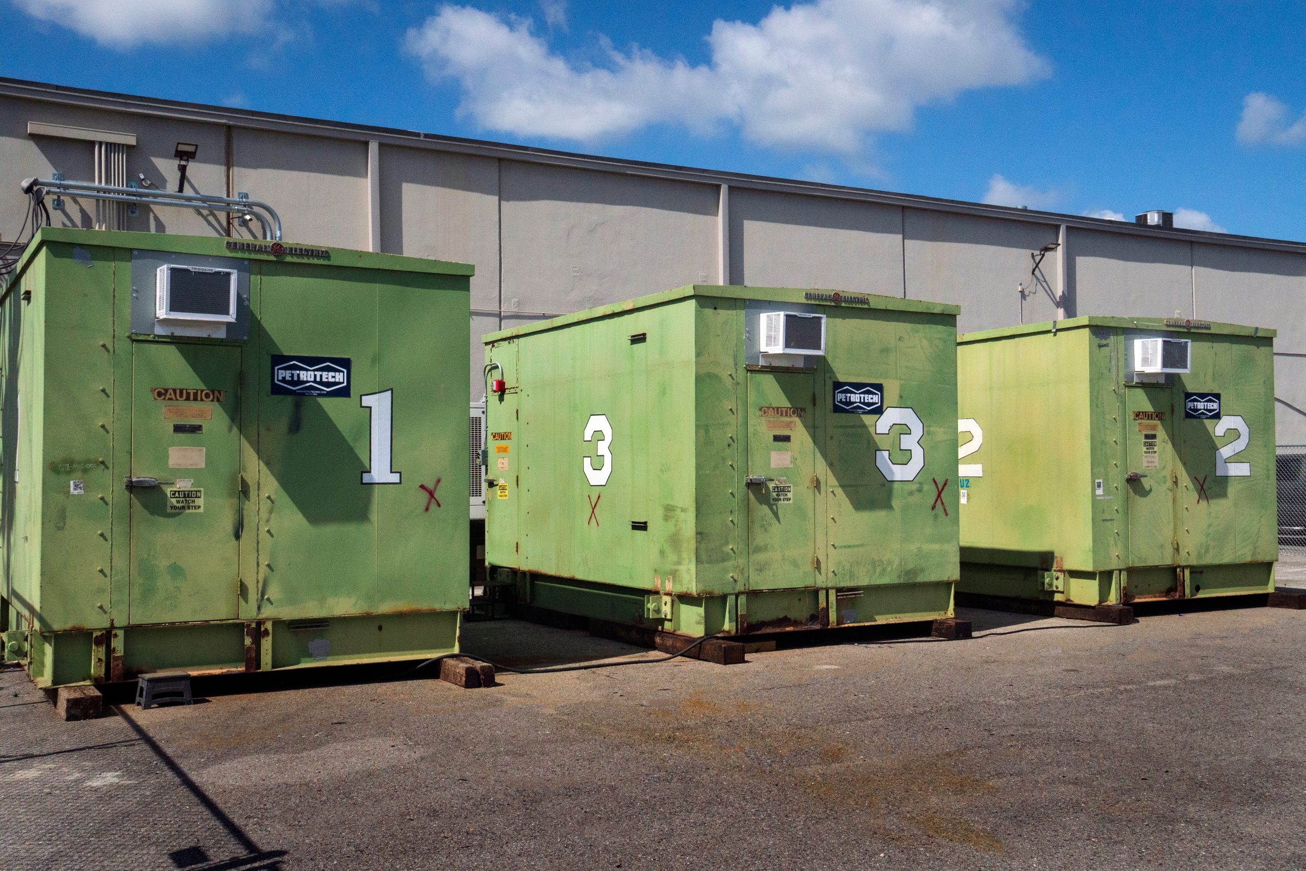Row of green packaged equipment enclosures outdoors