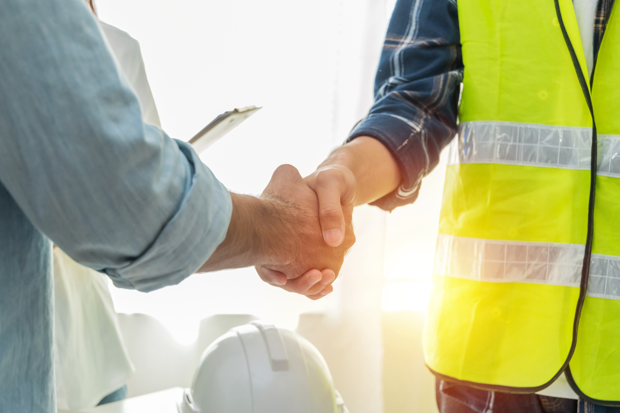 Handshake between a manager and a worker in a high-visibility vest
