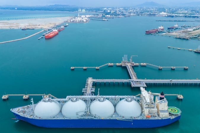 LNG carrier with cryogenic storage tanks at a terminal