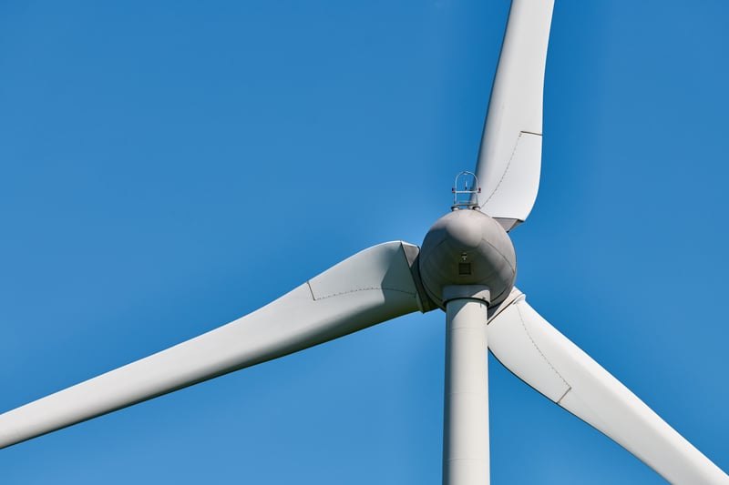 Close-up of a wind turbine hub and blades against blue sky